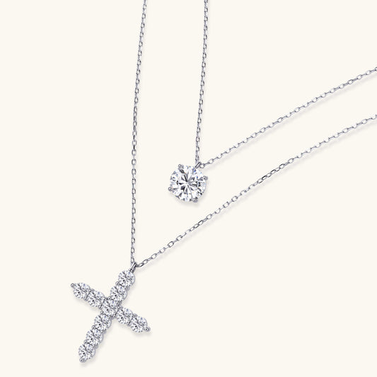 Two delicate sterling silver necklaces with moissanite stones - one solitaire pendant and one cross pendant on white background.