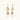 Gold sunburst charm earrings with baroque pearl drops on French hooks against cream background