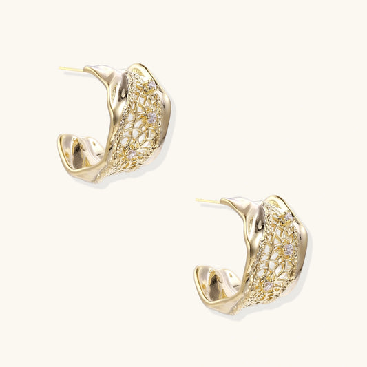 Gold-plated sculptural hoop earrings with geometric lattice centerband and sparkling zirconia on white background.