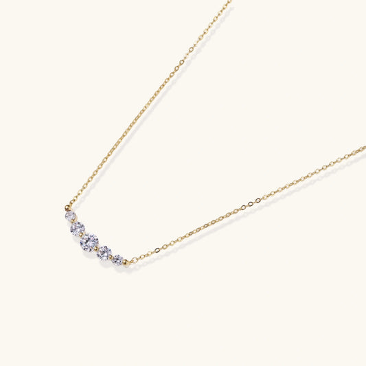 Delicate 14K gold-plated necklace with five graduated zirconia stones arranged in a curved arc on fine chain