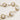 Gold wire-wrapped freshwater pearl bracelet with alternating pearl sizes on cream background, adjustable length