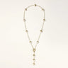 Gold-plated lariat necklace with baroque pearls and textured caps on cream background, showing adjustable Y-shaped design.