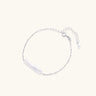 Minimalist bracelet with iridescent baroque pearl on rhodium-plated sterling silver chain against cream background