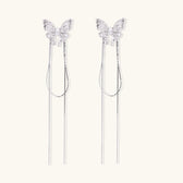 Pair of silver threader earrings with crystal butterfly tops and long chain drops on cream background.