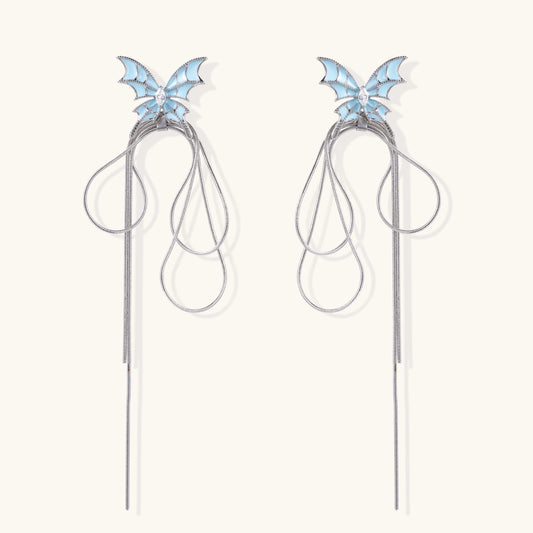 Long silver-tone earrings with powder blue enamel butterfly studs and flowing chain tassels on cream background