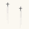Long silver threader earrings with ornate cross-star design and delicate dual chain tassels on white background
