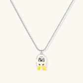 Chrome egg-shaped pendant with kawaii face, yellow bow, and pearl detail on silver chain against white background