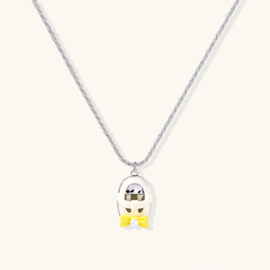 Chrome egg-shaped pendant with kawaii face, yellow bow, and pearl detail on silver chain against white background