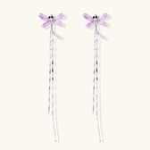 Long drop earrings with translucent lavender enamel dragonfly wings and white gold plated segmented bodies on white background