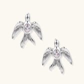 White gold-plated bird earrings with spread wings and oval zirconia center on cream background