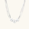 Sterling silver multi-strand necklace with three brushed round beads on cream background
