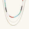 Multi-strand necklace with rainbow quartz beads and gold-plated chains on beige background