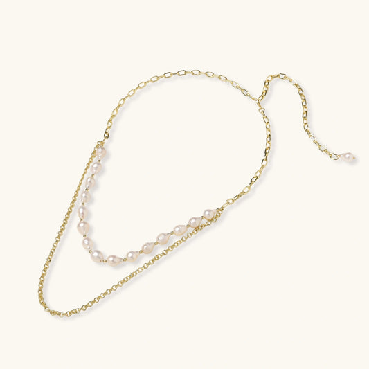 Layered gold chain necklace with organic baroque freshwater pearls and adjustable length on cream background