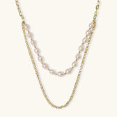 Layered gold chain necklace with organic baroque freshwater pearls and adjustable length on cream background