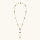 Gold-plated lariat necklace with baroque pearls and textured caps on cream background, showing adjustable Y-shaped design.