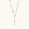 Y-shaped gold-plated necklace with white and gray freshwater pearls on cream background, showing adjustable drop design.