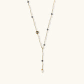 Y-shaped gold-plated necklace with white and gray freshwater pearls on cream background, showing adjustable drop design.
