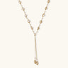 Adjustable gold lariat necklace with freshwater pearls nested in delicate cage settings and Y-shaped tassel drop