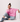 Woman wearing a pink sweater and blue pants sitting on a white surface.