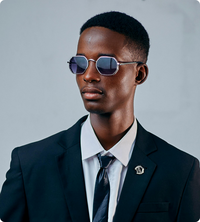 Man wearing a suit and sunglasses against a gray background