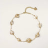 Gold-plated necklace with wire-wrapped shell pieces and freshwater pearls on neutral background, adjustable chain visible.